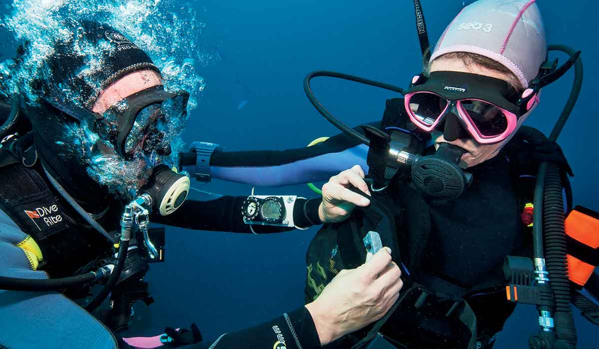 Male diver adds weights to the belt of his female companion