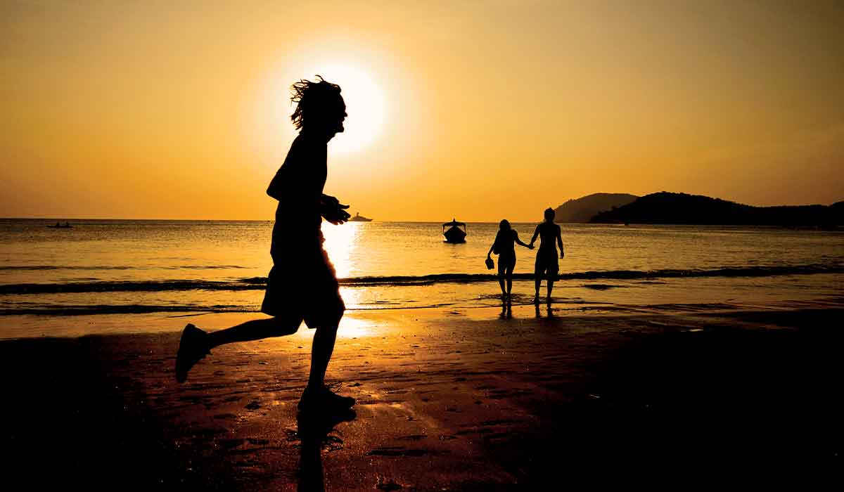 Male runner runs on a beach at sunset