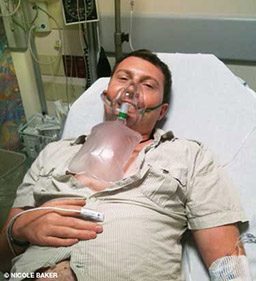 Man lies in hospital bed wearing an oxygen mask