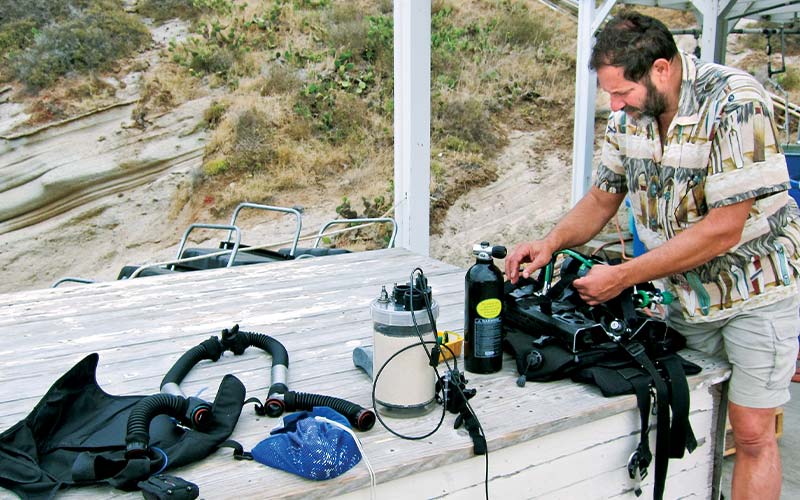 Man on a boat assembles rebreather dive gear