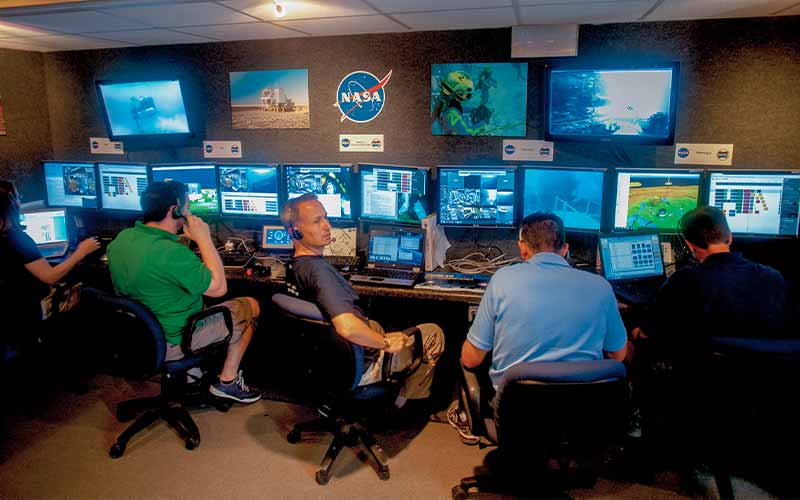 NASA staff monitor computers and watching divers during their underwater missions