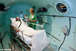 Nurse helps patient in hyperbaric chamber