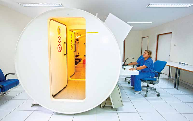 Nurse sits behind the desk of an available hyperbaric chamber