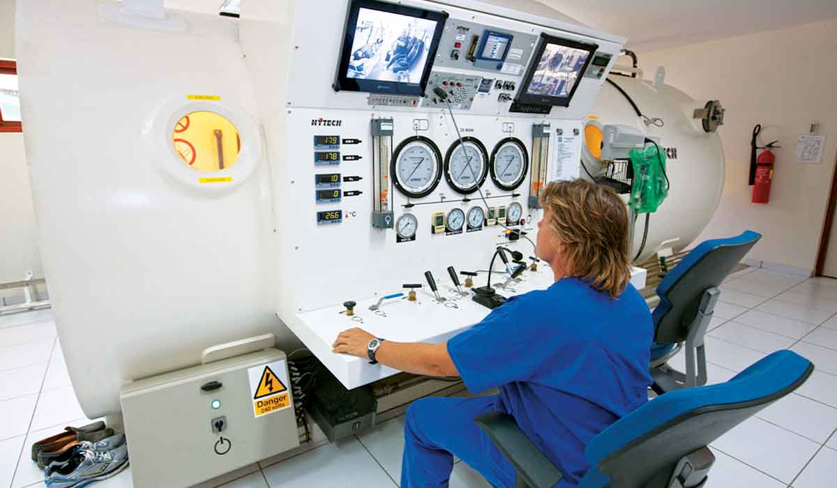 Nurse sits outside a hyperbaric chamber monitoring it