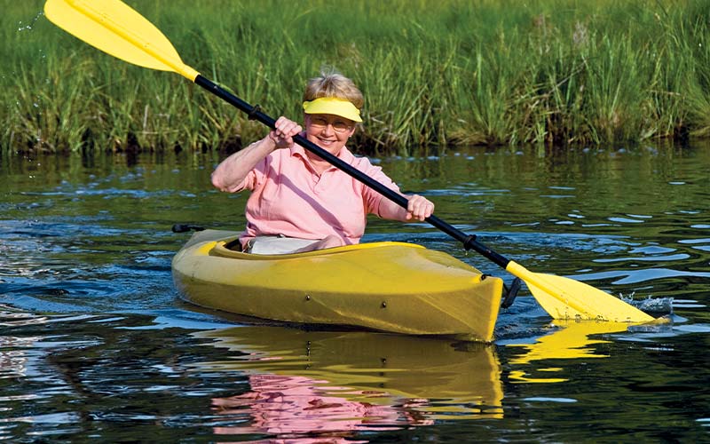 Old woman rows a yellow kayak