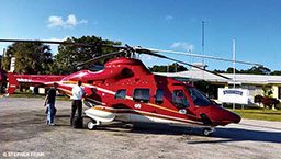 Red emergency helicopter with two people standing outside it