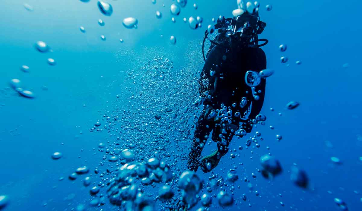 Scuba diver floats upward and is surrounded by bubbles
