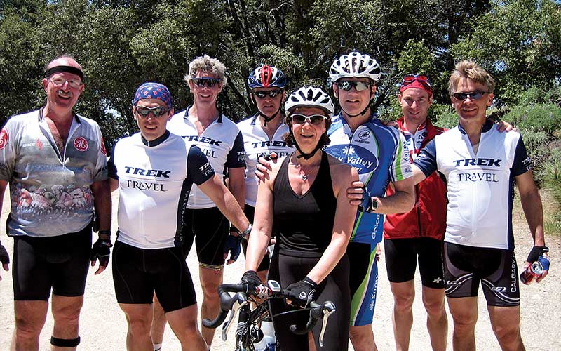 Seven male cyclists and one female cyclist pose for a photo