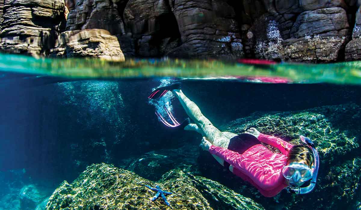 Snorkeler in pink rash guard swims just under water
