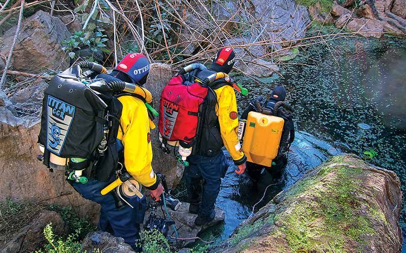 Three rebreather divers walk into the water