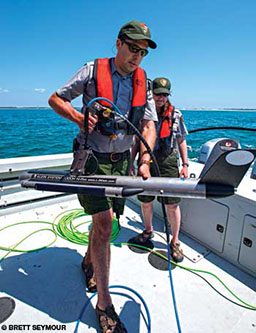 Two NPS rangers on a boat with a sonar detector
