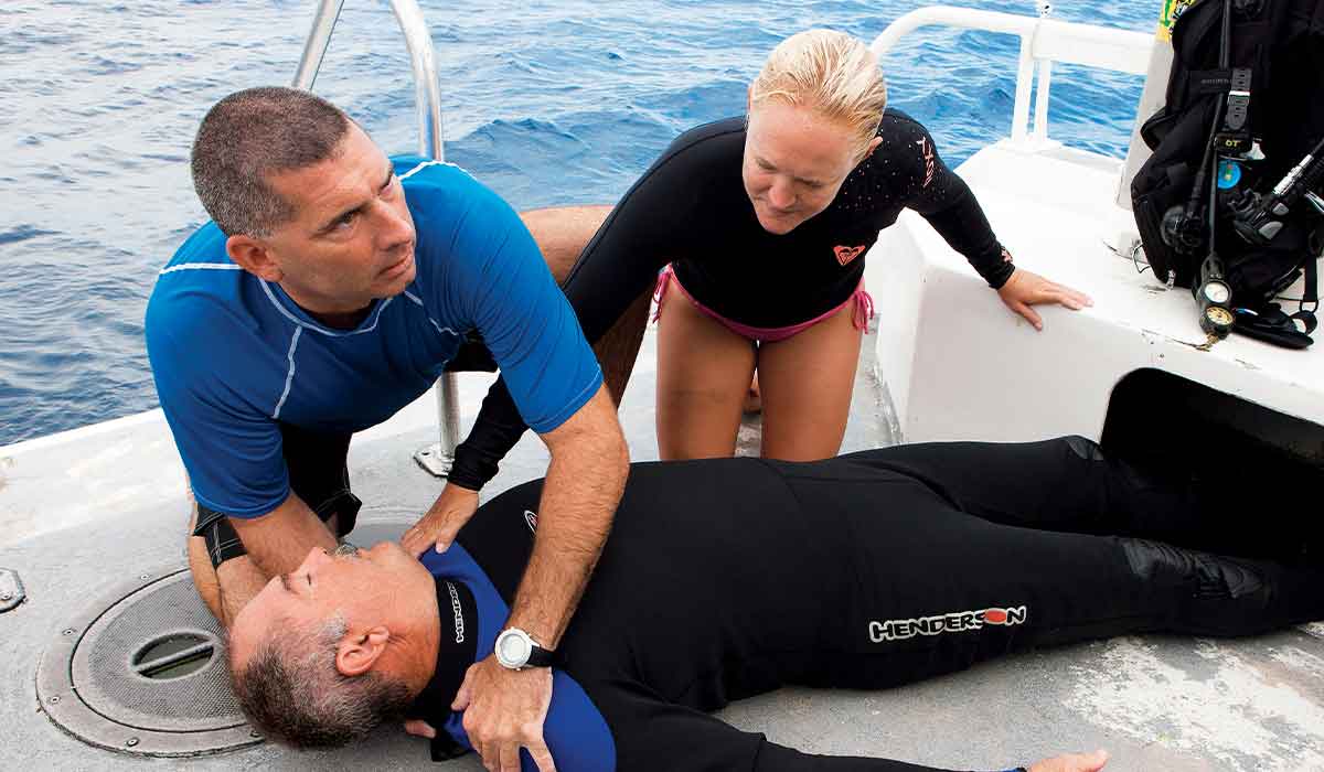 Two dive buddies assist an unconscious diver on a boat
