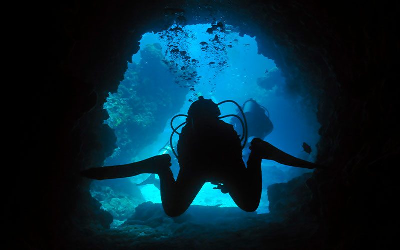 Two divers swim through a cave