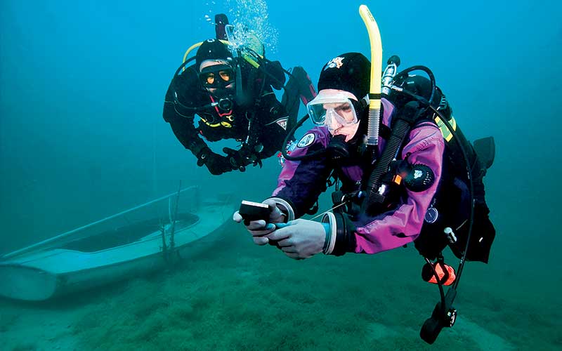 Two divers stare at an underwater communication device