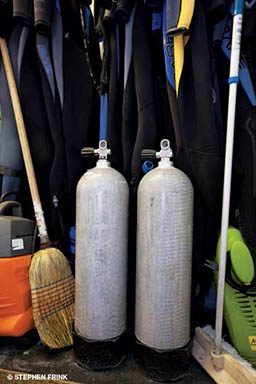 Two scuba tanks next to a broom