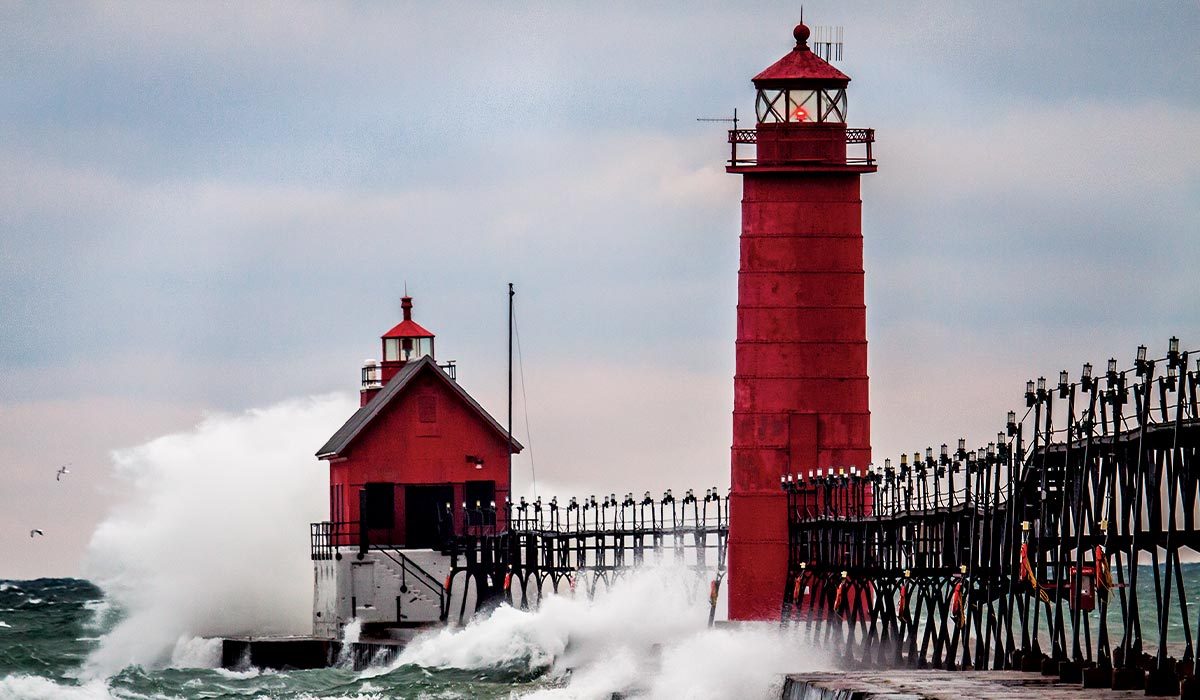 Waves crash against a red lighthouse