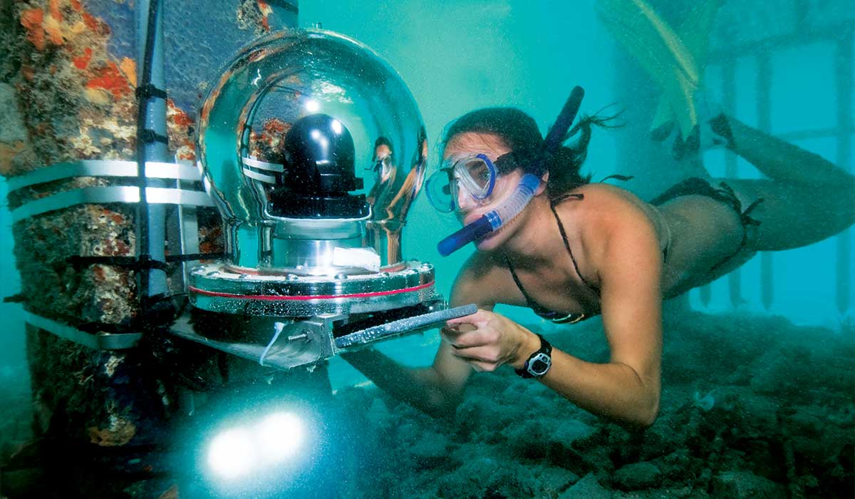 Woman holds an underwater camera and is wearing a snorkel