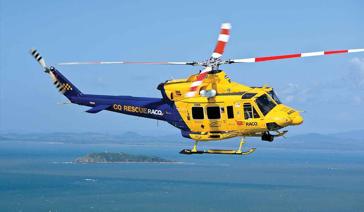 An Australian emergency helicopter, in yellow, flies through the skies