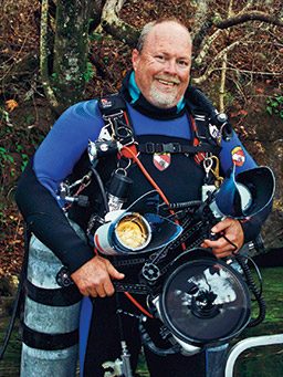 Bearded cave diver holds all the gear and poses for a photo
