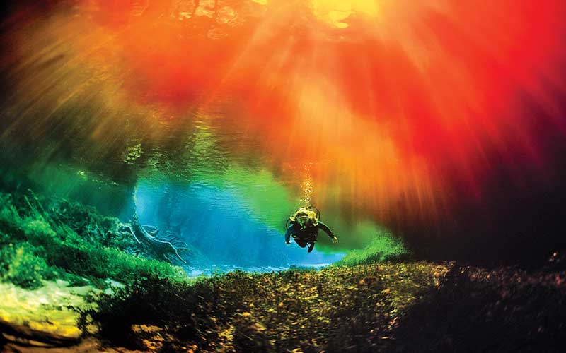 Cave diver swims through a curiously lit cave