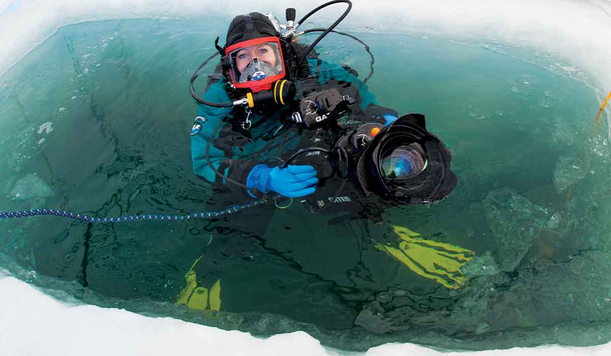 Dive pops up from hole in ice holding a communication system