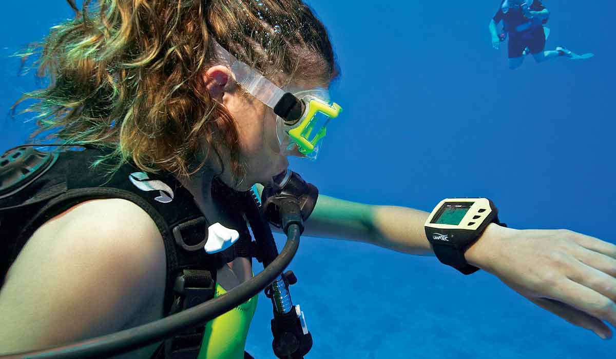 Female diver looks at dive computer attached to left wrist