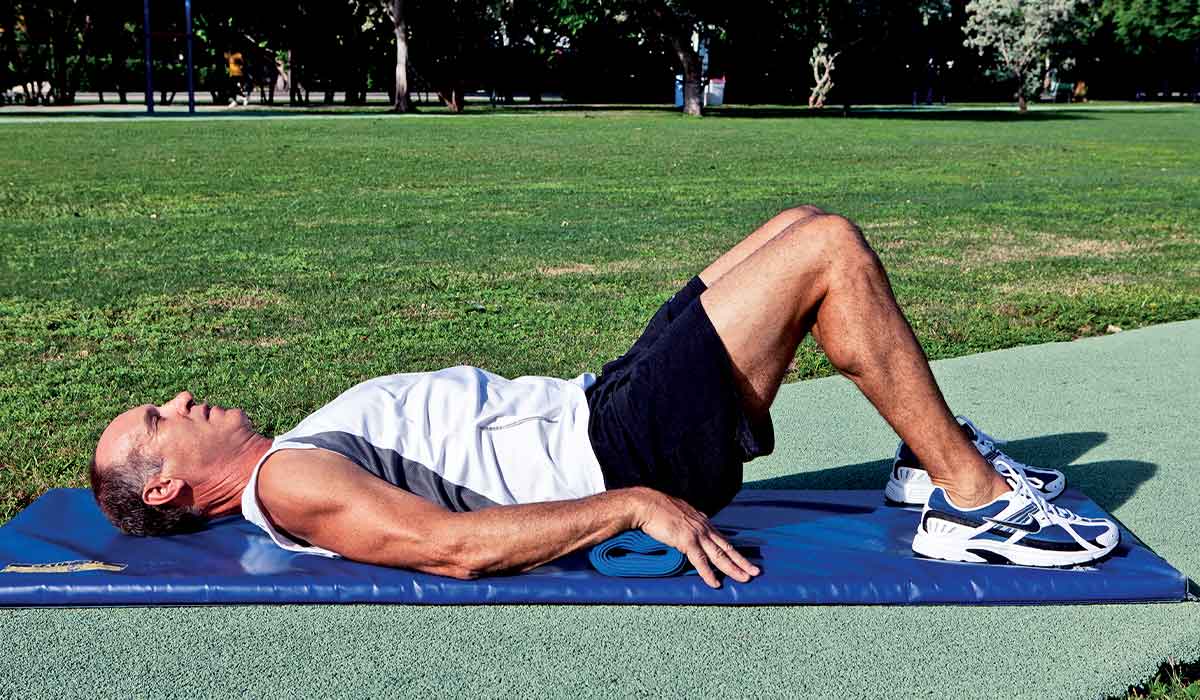 Man lies on blue mat with knees bent