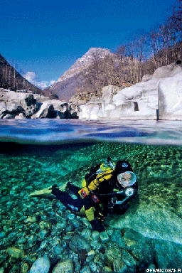 Over-under shot of diver in an icy high-altitude lake