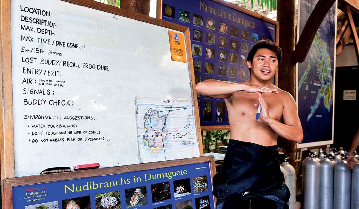 Shirtless dive master leads a predive check with white board