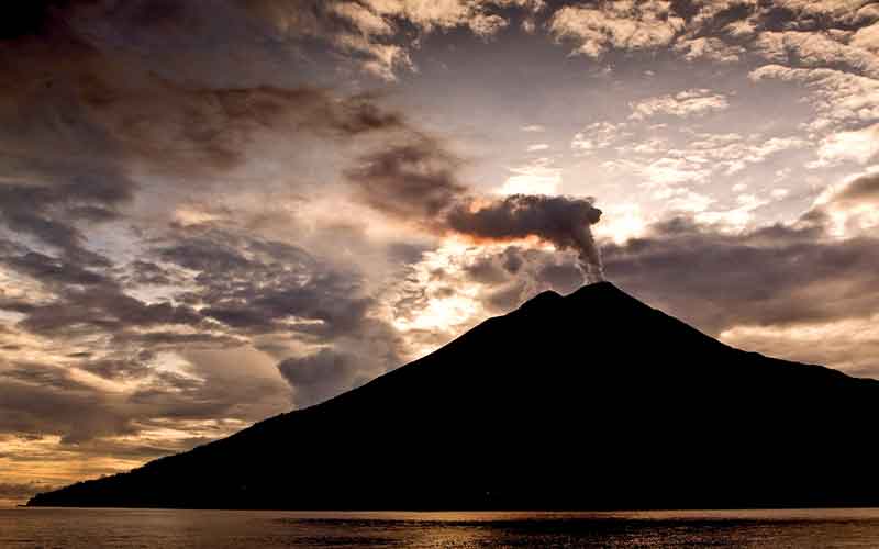 Smoking oceanside volcano at sunset
