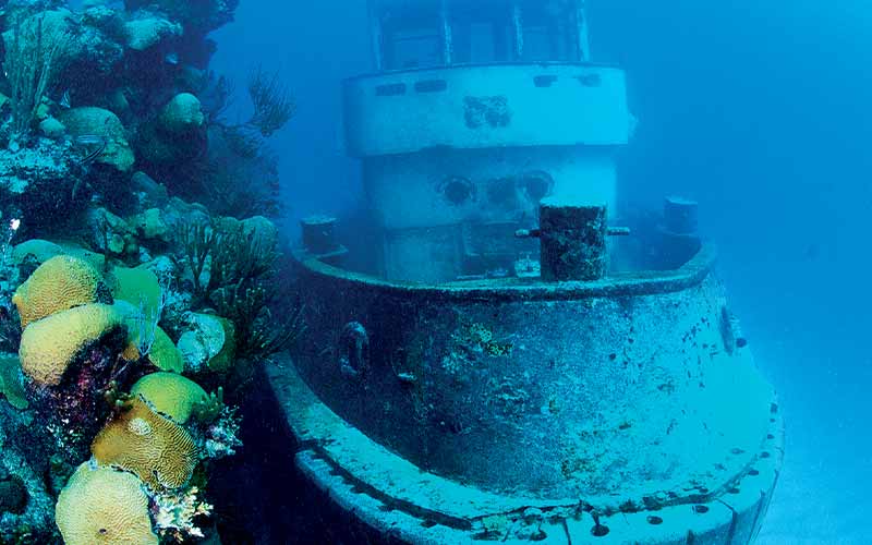 Sunken tugboat next to wall of coral reef