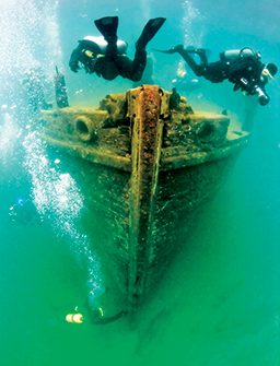 Two divers swarm a sunken ship, trying to get good views