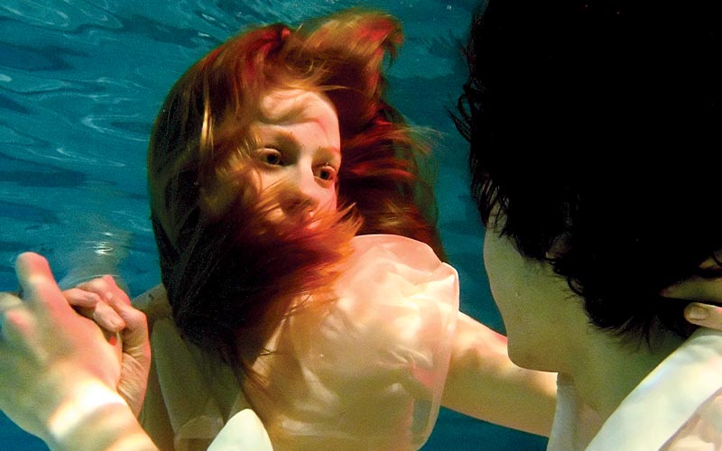 Submerged, a red-haired actress stares at a black-haired man