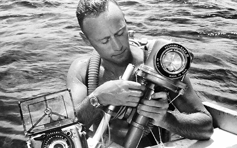 Black-and-white photo of a man assembling his camera