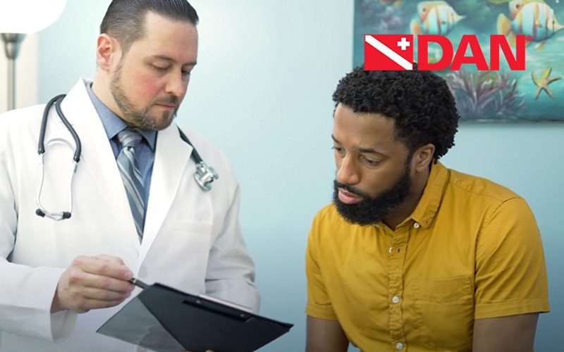 A Black patient in a yellow shirt gets advice from a bearded doctor