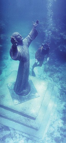 Diver floats next to a submerged statue of Jesus