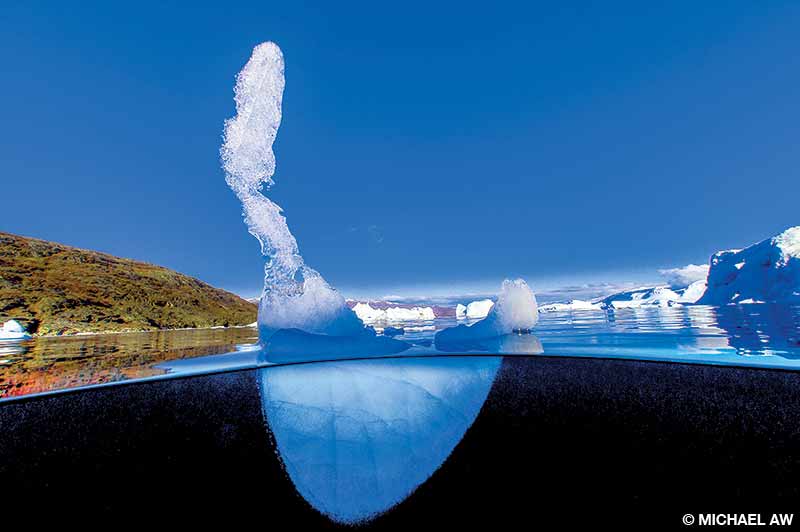 The remains of a once-mighty iceberg beneath a warm blue sky at Scoresby Sund, Greenland