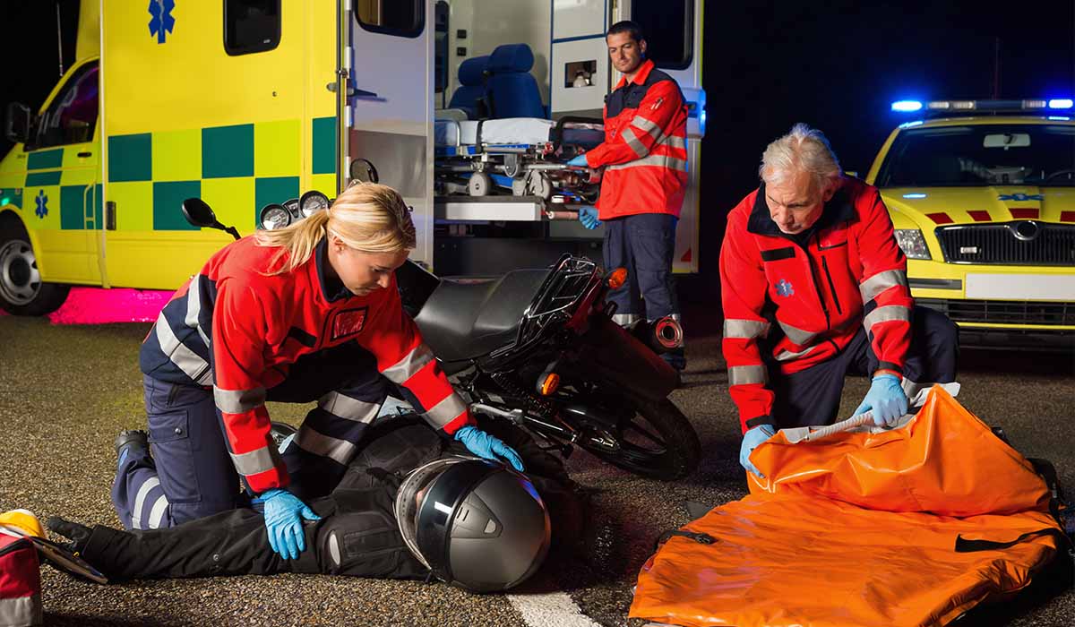 Three medics assist a motorcycle crash victim