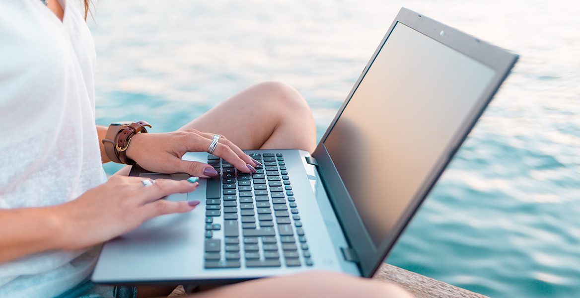 closeup of person working on laptop near water