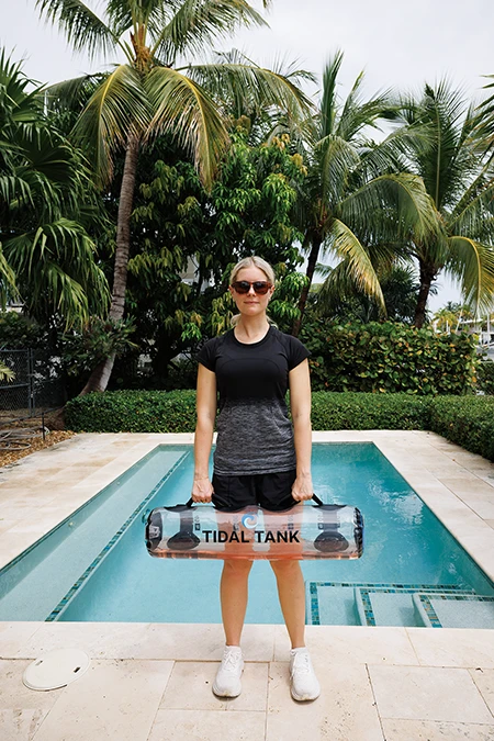 Woman starts with feet shoulder-width apart, holding the bag in front of her thighs.