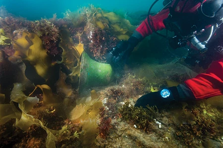UAT diver Filippo Ronca shines a light on the bell on the deck of the Erebus.