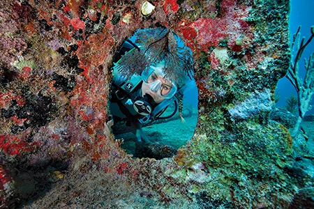 Diver poses inside a circular coral reef.