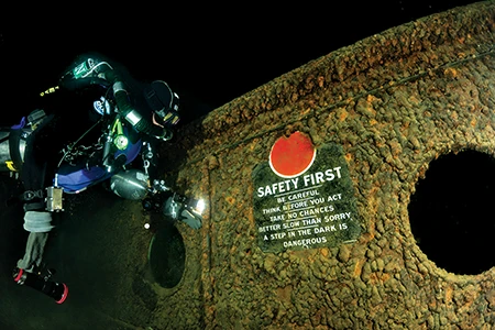 A sign on the Superior City reminds diver Terry Irvine that “a step in the dark is dangerous.” 