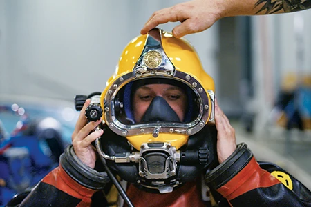 A diver dons a dive helmet