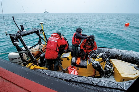 Divers get ready to execute the day’s mission on HMS Erebus from the UAT rigid-hulled inflatable boat as inclement weather conditions begin to escalate at the surface.